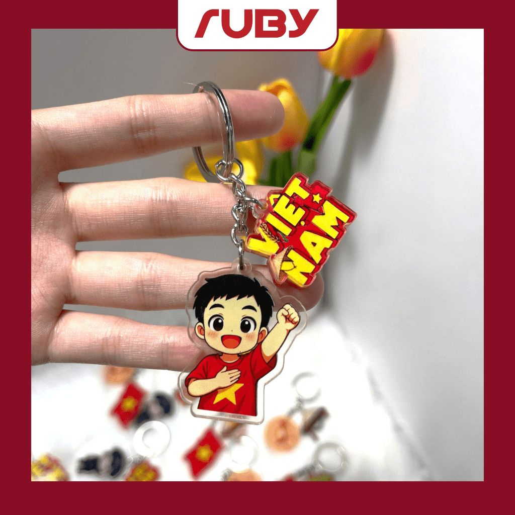 Móc khóa chibi thiếu nhi mặc áo đỏ sao vàng giơ tay, kèm biểu tượng chữ Việt Nam – thiết kế viền trong, sản phẩm Ruby dịp Quốc khánh 2/9.