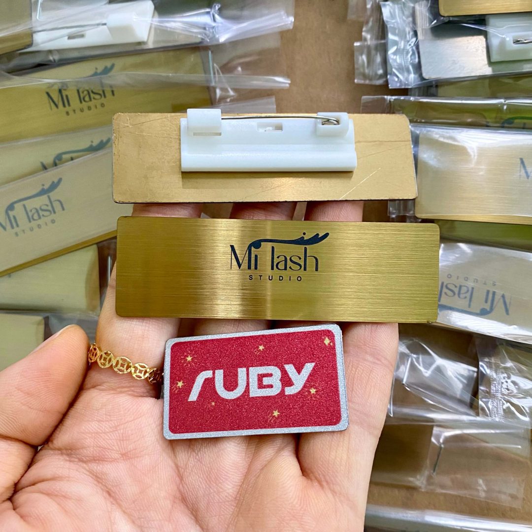 Bảng tên Mi Lash Studio inox vàng xước, khắc laser logo, kim gài